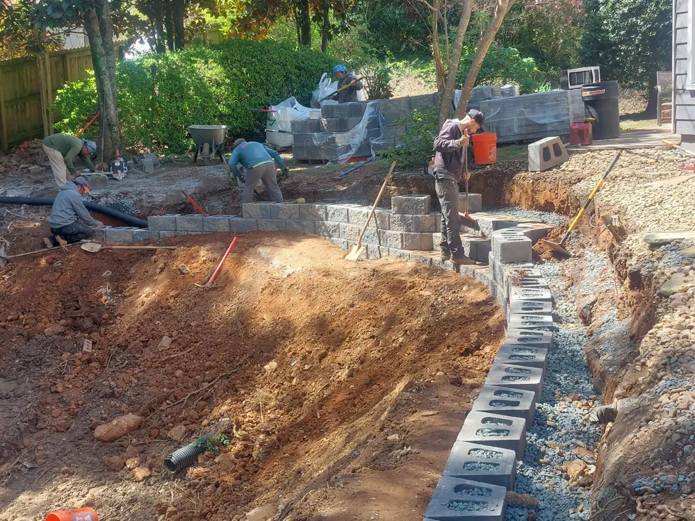 A Georgia's Best Property Masters crew setting the base course of a block retaining wall over drainage stone