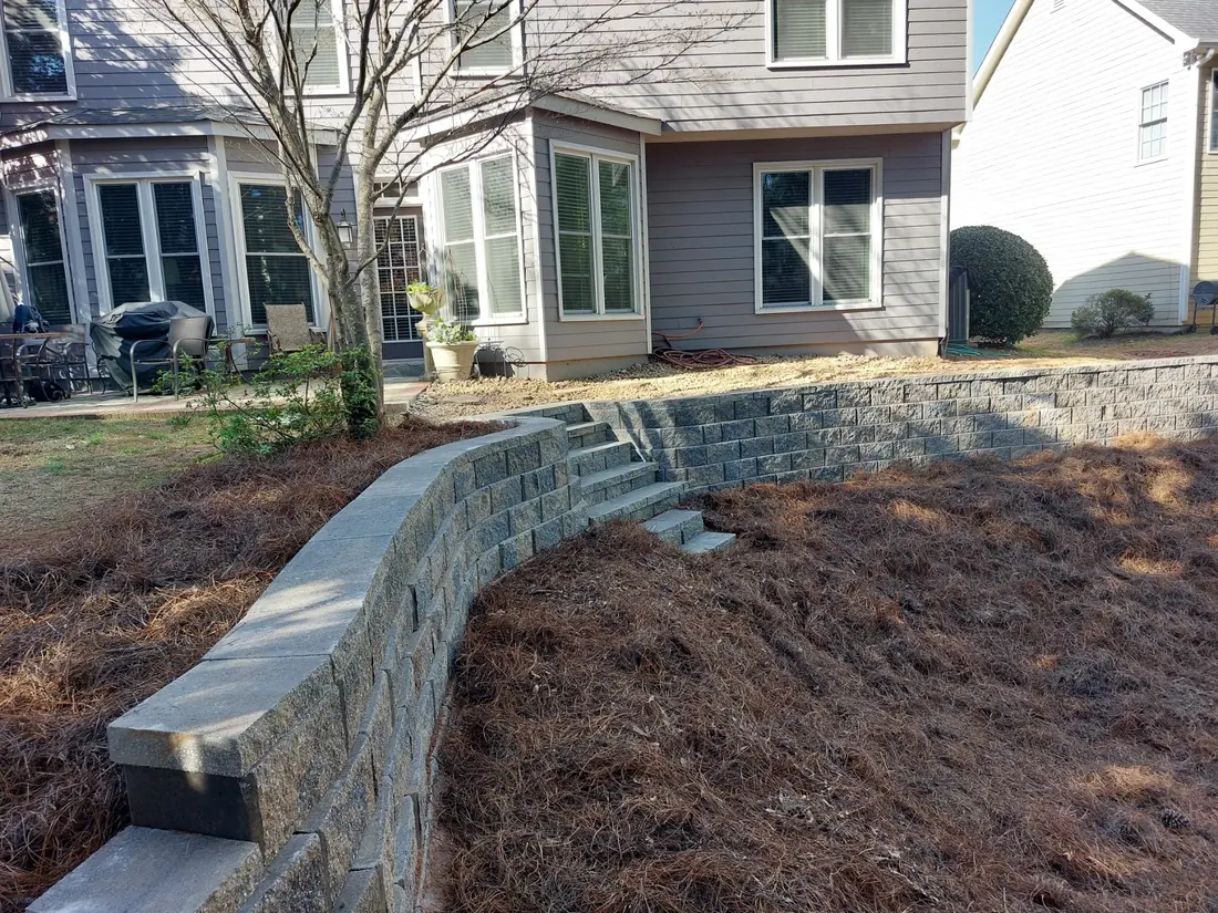 Curved block retaining wall with a finished cap holding back a pine straw bed